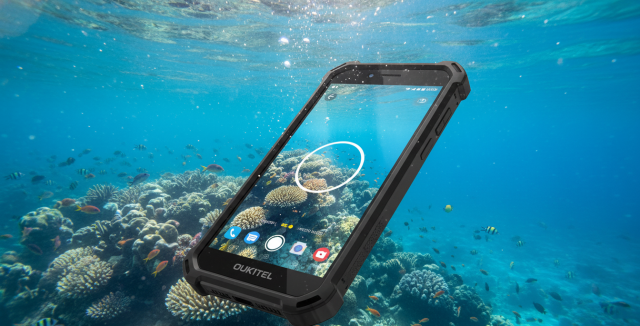Smartphone Oukitel WP60 sumergido en agua cristalina realizando una fotografía subacuática de arrecifes.